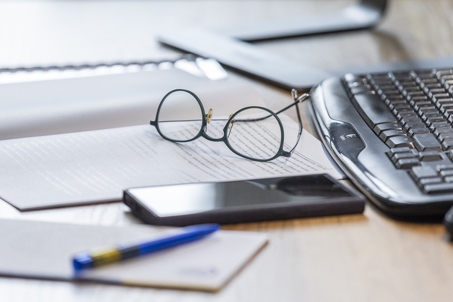 Arbeitsplatz in Großaufnahme, Notizbuch, Tastatur, Büro, Handy, Brille