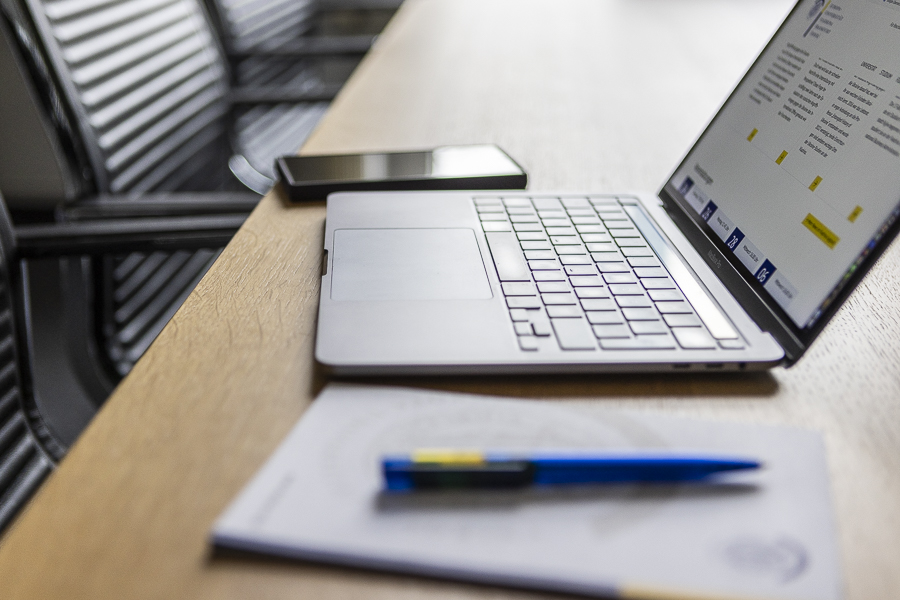 der Arbeitsplatz, der Laptop, der Stift auf dem Notizzettel, das Handy