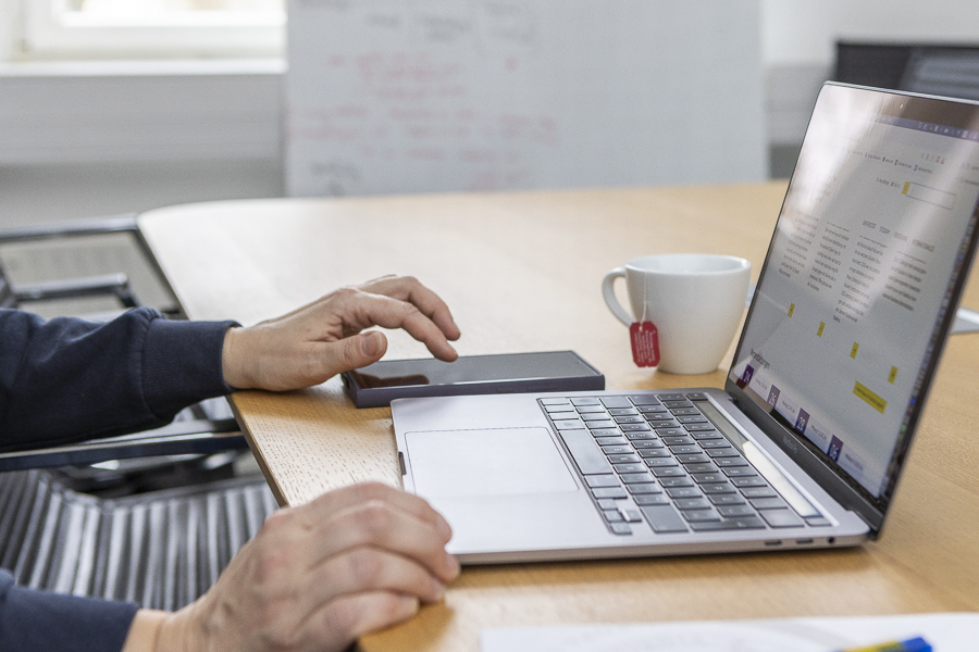 Person arbeitet am Laptop, die Teetasse, das Handy