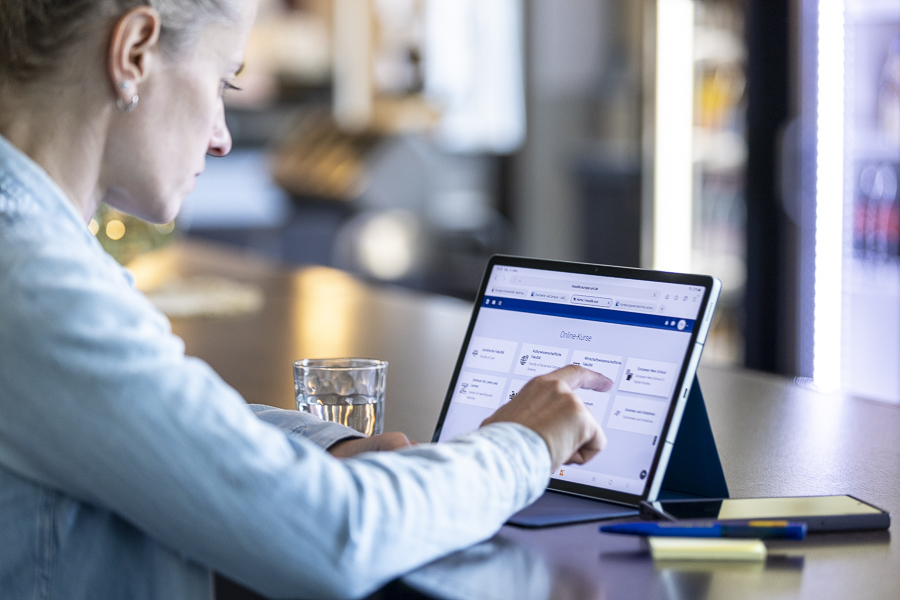 Frau arbeitet am Tablet, Wasserglas, Handy, Seitenansicht